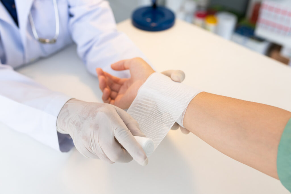 Close-up hand wear medical gloves  Of Doctor Hand Tying Bandage On The hand Of Patient In Clinic, osteophytes and heel, fascia