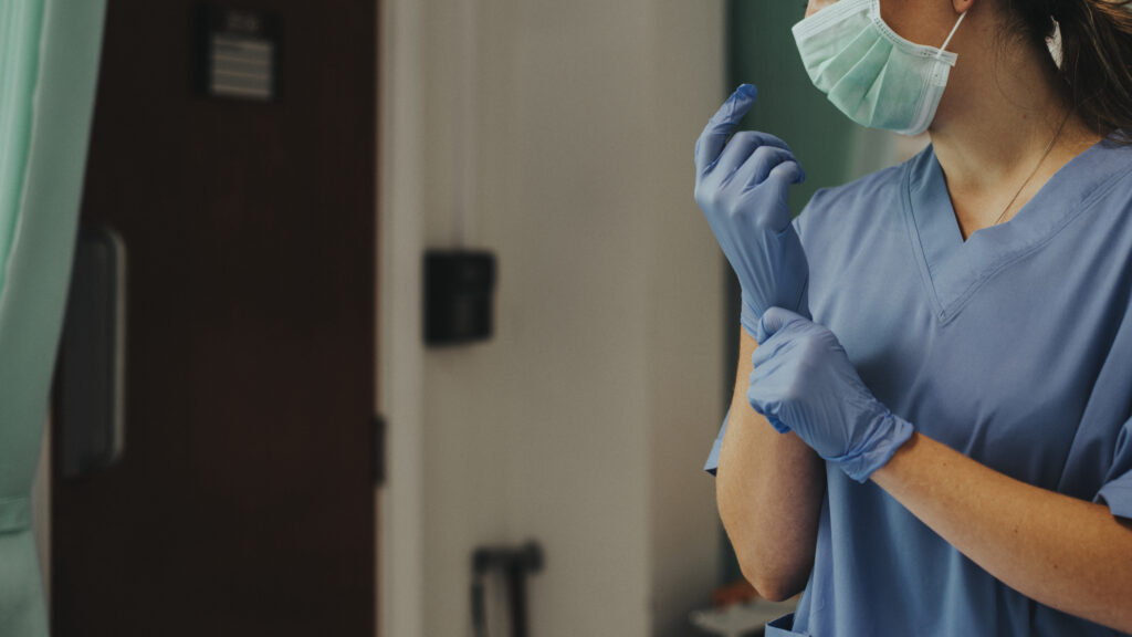 Doctor putting on a glove to prevent coronavirus contamination